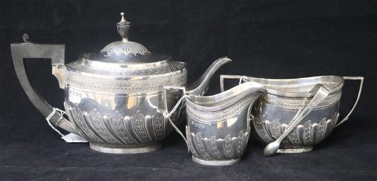 A late Victorian silver three piece tea set by Edward Hutton, London, 1893 and a pair of Irish silver sugar tongs, gross 28oz.